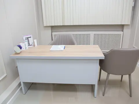 A calm, tidy consultation desk with two chairs in a bright room