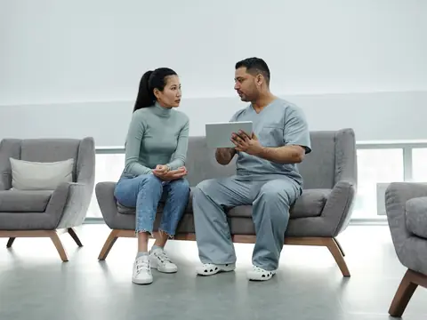 Two people on a sofa in a bright room looking over a tablet together