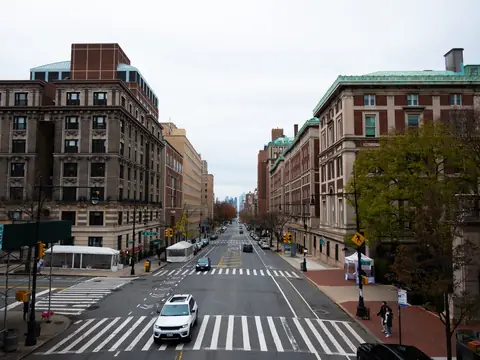 A Manhattan avenue in daylight with a wide crosswalk and brick buildings